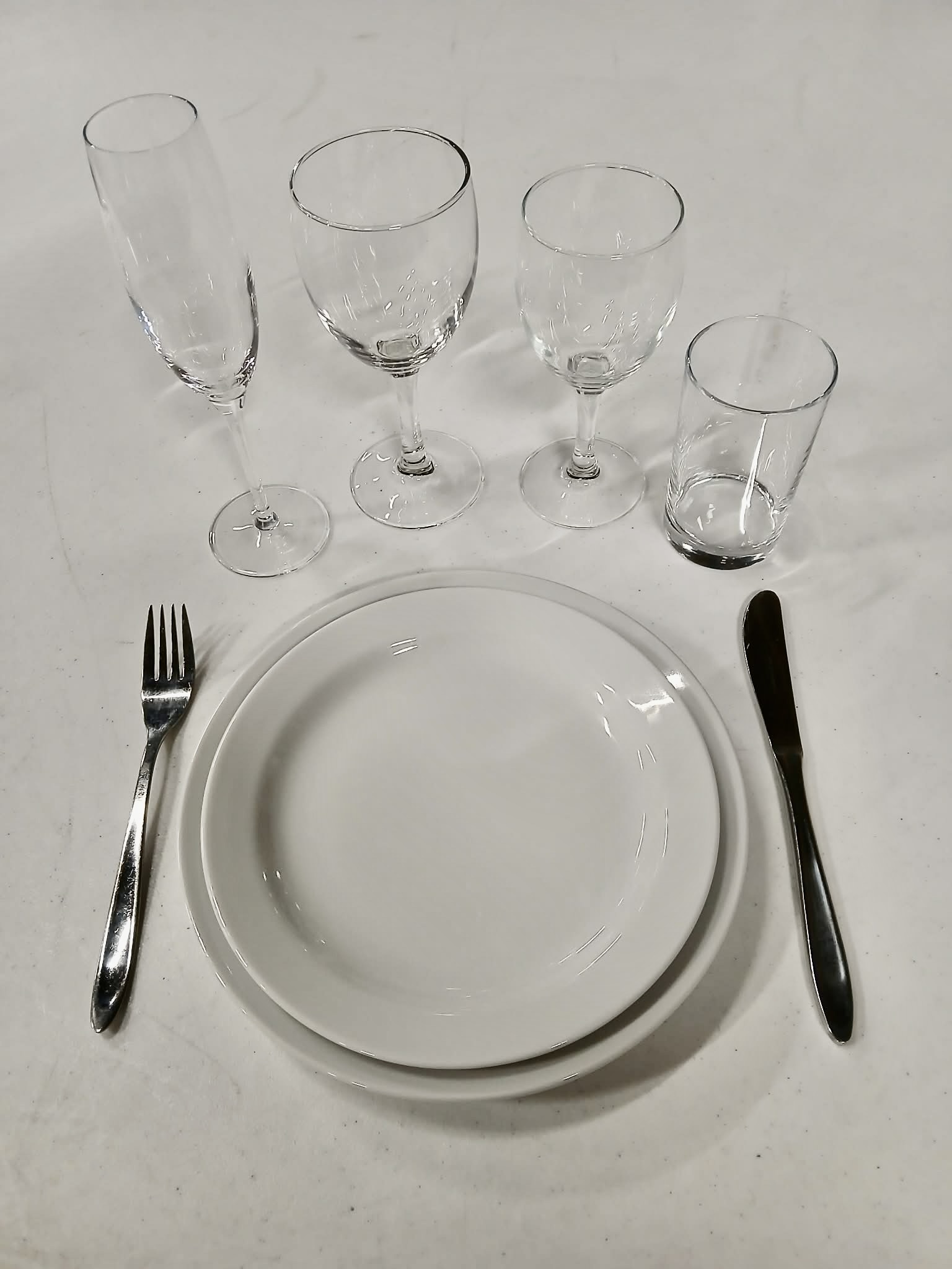 Eight shirts arranged on table in black, olive, grey, blue, white, red, mustard, and green.