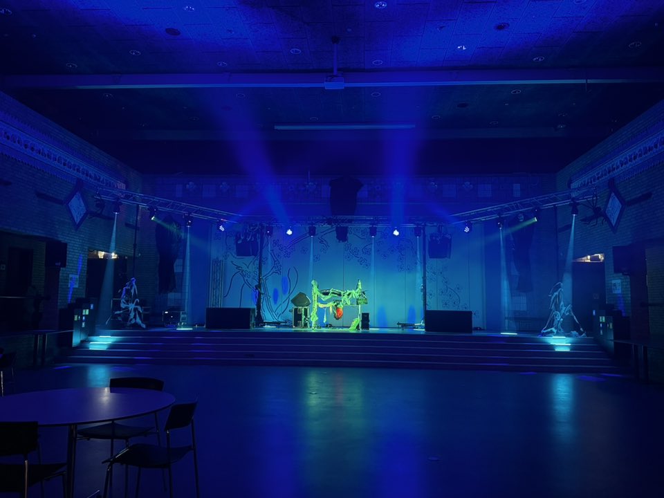 Eight shirts arranged on table in black, olive, grey, blue, white, red, mustard, and green.