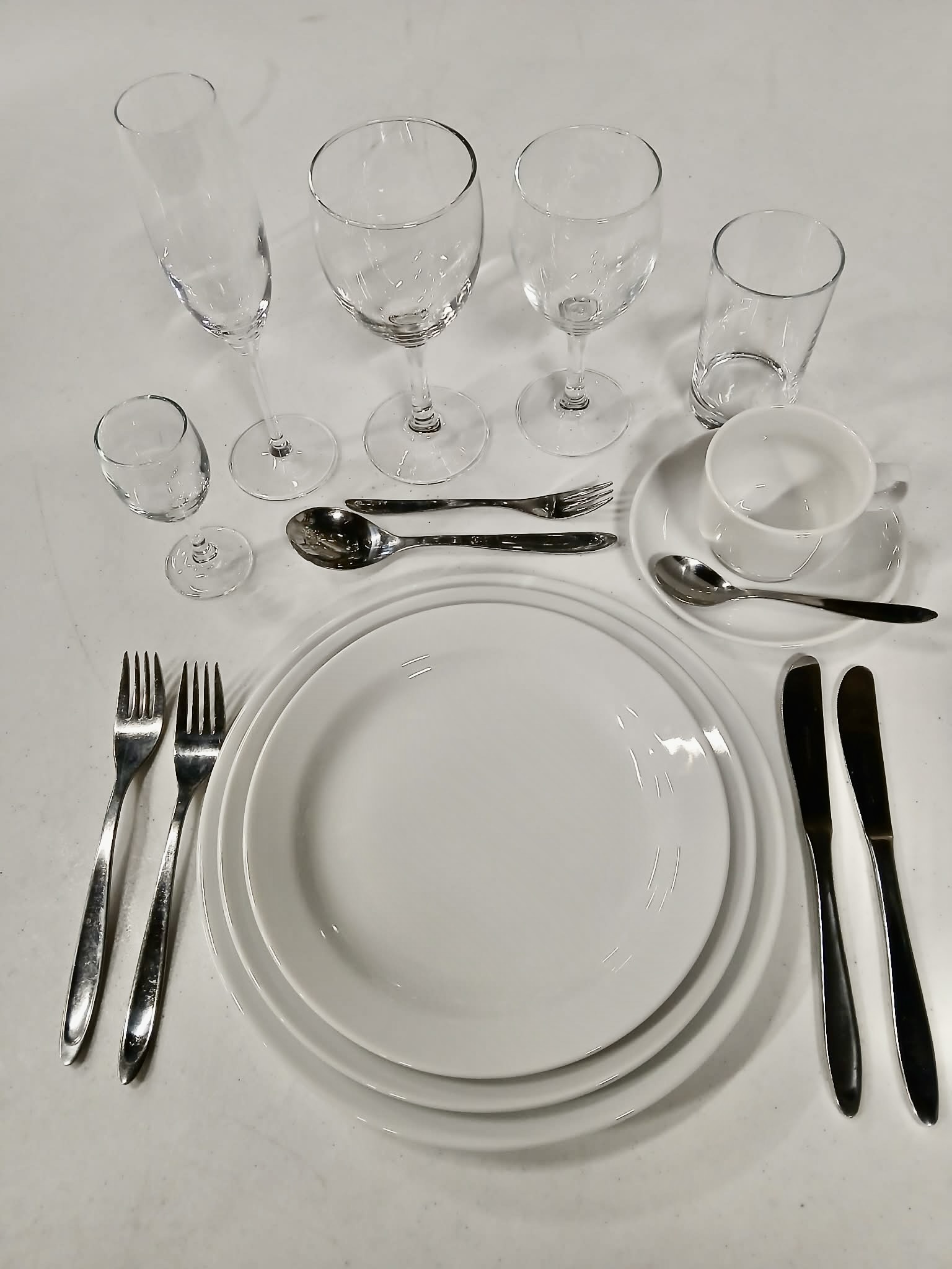 Eight shirts arranged on table in black, olive, grey, blue, white, red, mustard, and green.